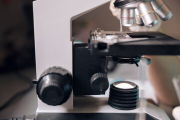 Dripping transparent liquid onto glass slide at contemporary microscope in lab