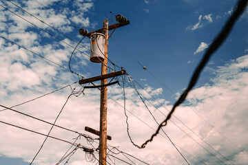 Low angle shot of an electric pole on the cloudy sky background