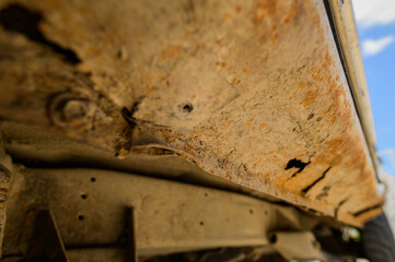 Body repair and welding work required. Rust on a gray old car. Rust hole on an old worn out painted metal surface.