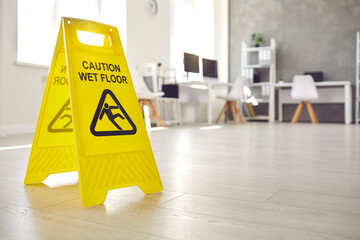 Close up shot of plastic standing sign that reads Caution Wet Floor and has figure of man who slips...