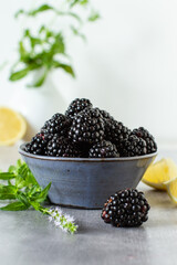 Bowl with fresh blackberries on a grey table