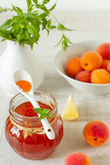 Jar with homemade apricot jam and fresh fruits on a table