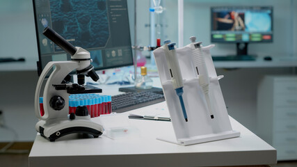 Scientific micropipette and microscope in laboratory designed for modern treatment innovation. Close up of chemistry equipment on workplace desk for professional microbiology researcher