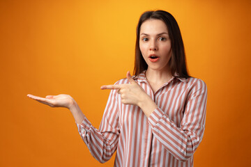 Fototapeta premium Young positive woman points fingers at copy space