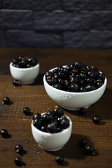 ripe black currants in cups on a wooden table