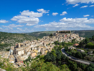 Fototapeta na wymiar Ragusa Ibla between the green mountains and the blue sky over Valle dei Ponti