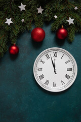 Fototapeta na wymiar Christmas and Happy New Year Festive background with fir tree branches, christmas decoration and clock that shows New Years Eve
