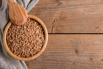 Wholegrain uncooked raw spelt farro in bowl on the wooden background