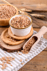 Wholegrain uncooked raw spelt farro in bowl on the wooden background, food cereal background, close up
