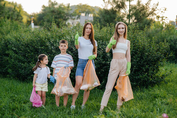 A group of girls with children at sunset are engaged in garbage collection in the park....