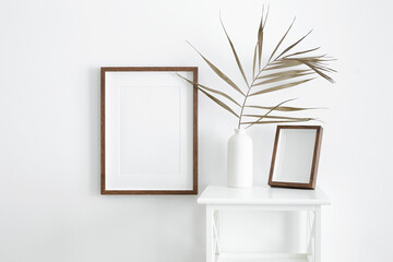 Stylish frames mockup for artwork, print or photo presentation. Blank wooden frames on white wall...