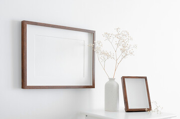 Blank landscape and portrait frames mockup on white wall with dry gypsophila plant decorations....