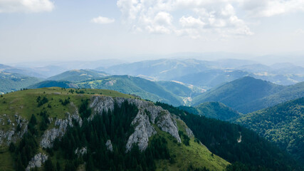 Aerial view of mountains covered with coniferous forests. Flying above a spectacular gorge in Kopaonik Serbia. Aerial beautiful dramatic cloudy sky with mountain view during sunset.