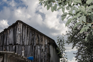 Old weathered barn in blue sky and puffy clouds. Rural landscape with old silver barn