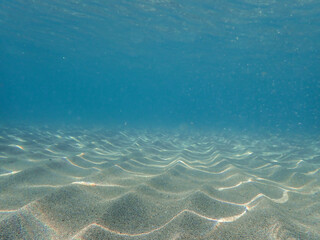 Underwater in the sandy sea, undersea, diving to the ocean bottom, under ocean, crystal clear water, blue water surface, Tropical sandy beach in Mediterranean sea, under water, Sunlight under the sea.