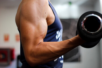 Fototapeta na wymiar detail of a man's arm performing biceps exercise in the gym