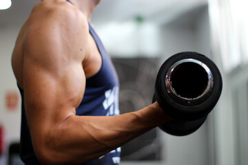Fototapeta na wymiar detail of a man's arm performing biceps exercise in the gym