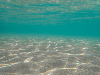 Underwater in the sandy sea, undersea, diving to the ocean bottom, under ocean, crystal clear water, blue water surface, Tropical sandy beach in Mediterranean sea, under water, Sunlight under the sea.