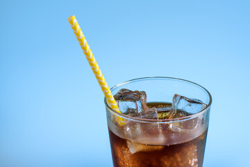 A glass of cola with ice on blue background