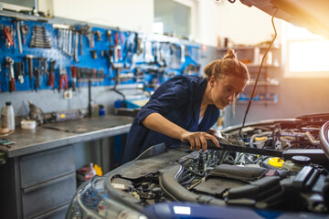 Female mechanic working on car tyre service. Portrait Of Female Auto Mechanic Working Underneath...