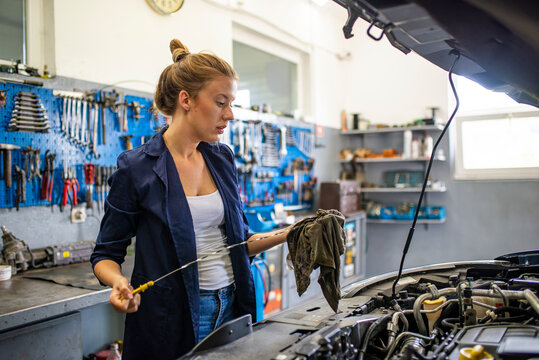 Cheerful female car technician enjoying working at the garage, copy space. Repair, car service concept Auto car repair service center. Female auto mechanic