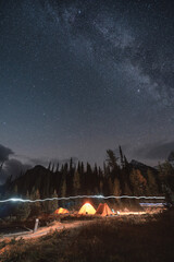 Camping tents with milky way in the night sky on campsite in autumn forest at national park
