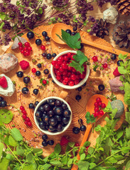 In two ceramic cups, black and red country currants lie to the edge