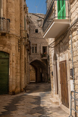 klasyczna, wąska uliczka miedzy kamienicami w miasteczku na południu Włoch - obrazy, fototapety, plakaty