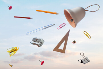 Flying school supplies after ring bell blue sky background. Back to school concept.
