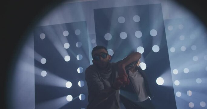 4K Professional Hip Hop , freestyle or swag dancers . Stylish young couple dancing crazy modern dance near decorative walls with many circle holes and spotlight . Shot on RED HELIUM Cinema Camera .