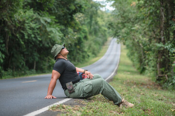 Backpackers travel by hiking and hitchhiking tourists. to travel to the destination. Tourists hitchhike, waved to help me, sat exhausted on the roadside to travel on foot in Khao Yai National Park.