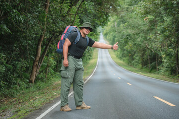 Backpackers travel by hiking and hitchhiking tourists. to travel to the destination. Tourists hitchhike, waved to help me, sat exhausted on the roadside to travel on foot in Khao Yai National Park.