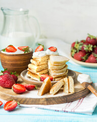 American breakfast. Pancakes with butter cream and strawberries. Berry dessert with milk. Summer breakfast with fresh berries