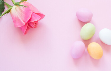 Marzipan Easter eggs in pastel colors and a rose in the pink background, top view with copy space