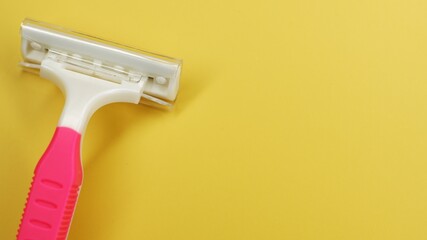 Pink disposable razor on a yellow background