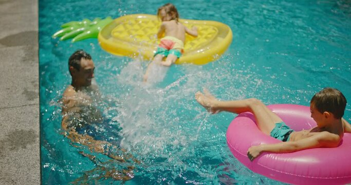 Family playing and splashing in the pool on summer vacation, cinematic family lifestyle