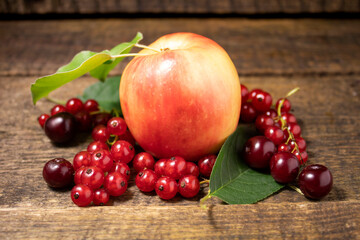 Apple, cherry and red currant lying on a wooden table.Fresh bright fruits and berries on a wooden background.