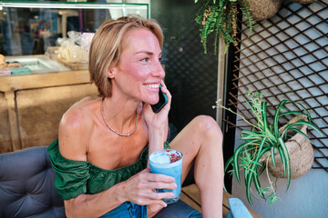 adult skinny woman using smartphone and a healthy smoothie - obrazy, fototapety, plakaty