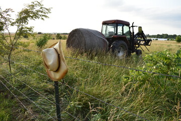 Tractor with a Hay Bale in a Field - obrazy, fototapety, plakaty