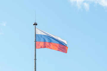 he flag of the Russian Federation on the background of the blue sky is developing in the wind