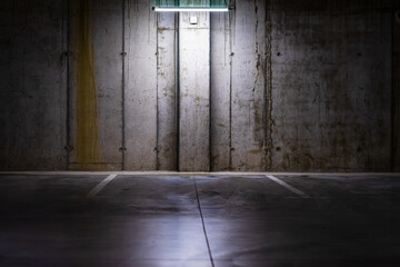 Empty parking lot with overhead dim light, underground parking garage.