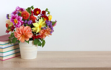bouquet of bright dahlias and a stack of textbooks .