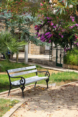 The white empty bench in the shade under the blooming trees, Korcula island, Croatia