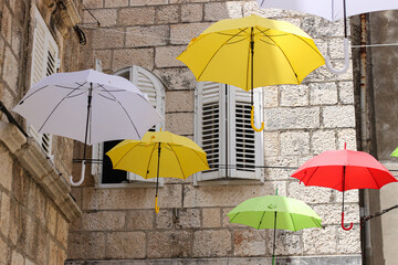 Fototapeta na wymiar The hanging colorful umbrellas with the background of a stone wall, Korcula island, Croatia