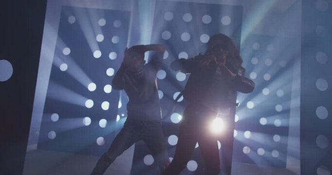 4K Professional Hip Hop , freestyle or swag dancers . Stylish young couple dancing crazy modern dance near decorative walls with many circle holes and spotlight . Shot on RED HELIUM Cinema Camera .