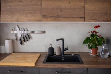 Modern kitchen in grey colors and wooden cupboards at home with kitchenware