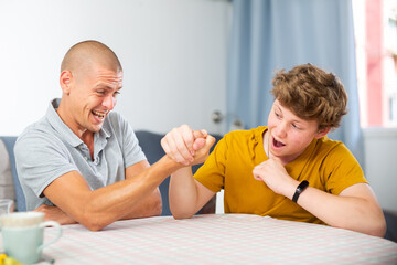 Fototapeta premium Father and his son doing arm wrestling on table