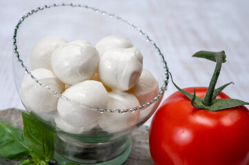 Fototapeta na wymiar Fresh white soft mini mozzarella balls served with red tomato and fresh green basil