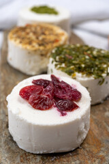 Cheese collection, variety of fresh white soft goat French cheeses with aromatic herbs, berries and green pesto