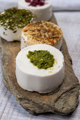 Cheese collection, variety of fresh white soft goat French cheeses with aromatic herbs, berries and green pesto